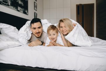 happy-family-lying-under-white-blanket-on-bed-2026-09-21-06-04-23-utc
