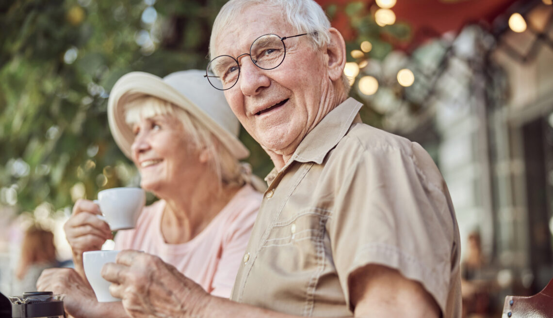 Modern elderly couple sitting in an outdoor cafe