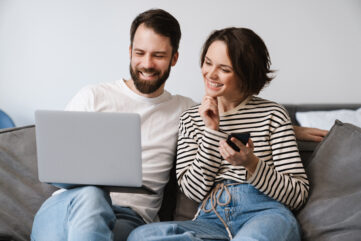 Happy young white couple sitting on a couch at home