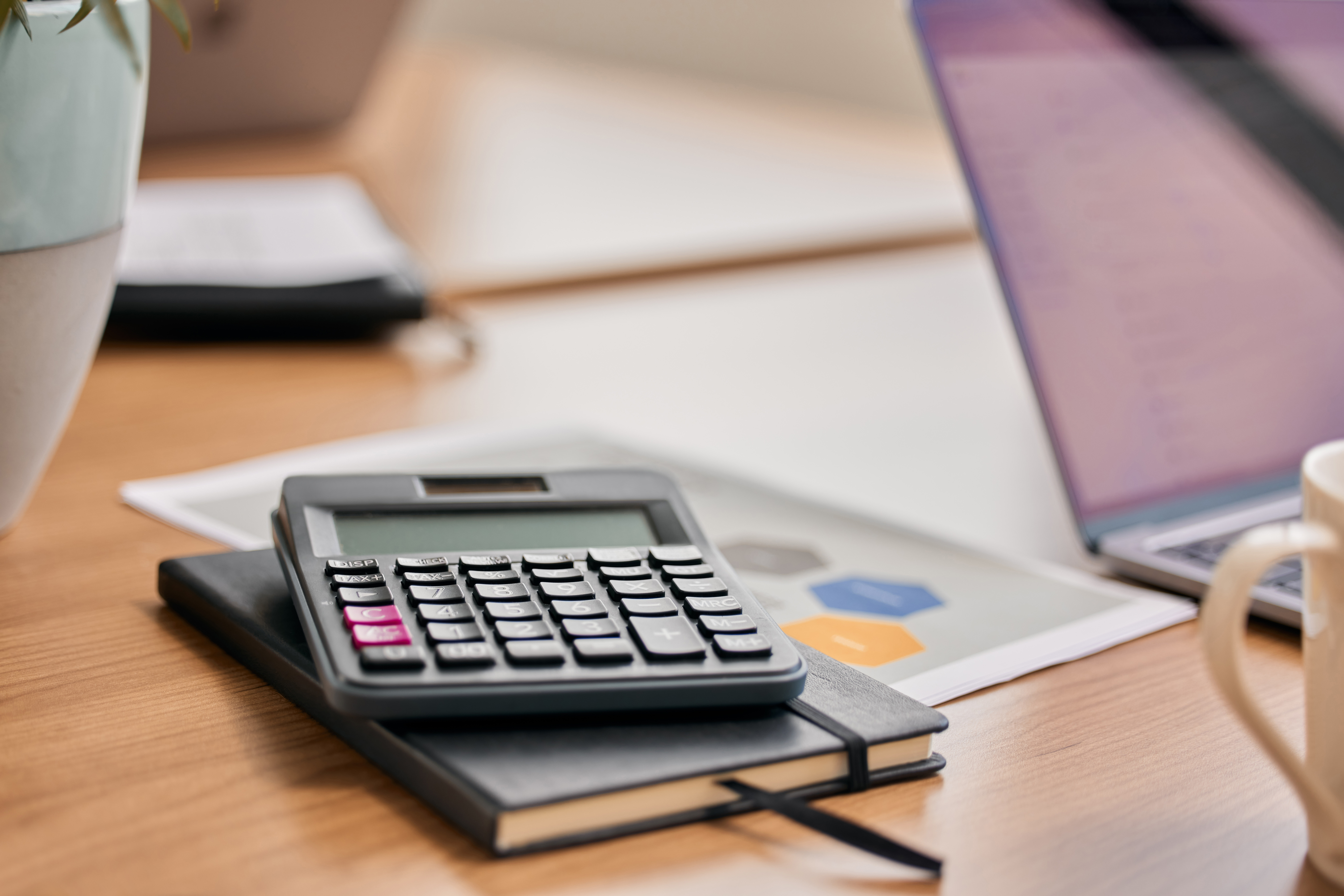 Still life shot of a calculator and notebook on a desk in an office.